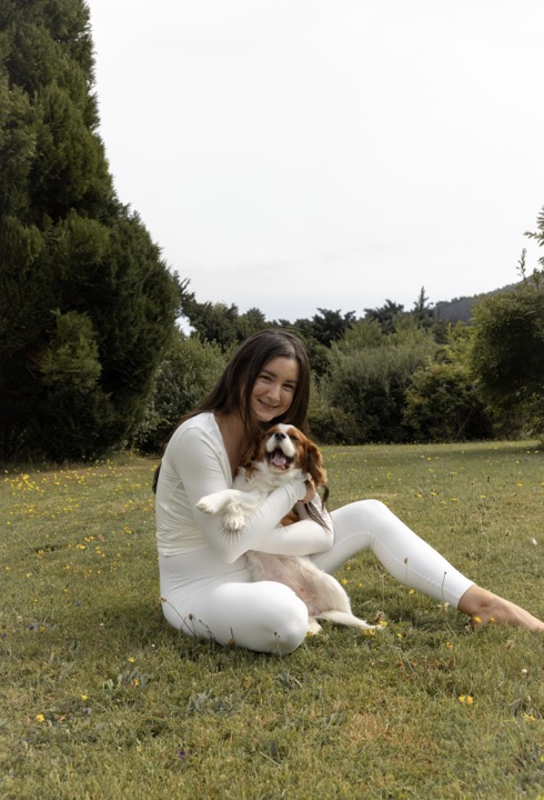 Melissa Tarpey sitting in a wildflower meadow with her dog